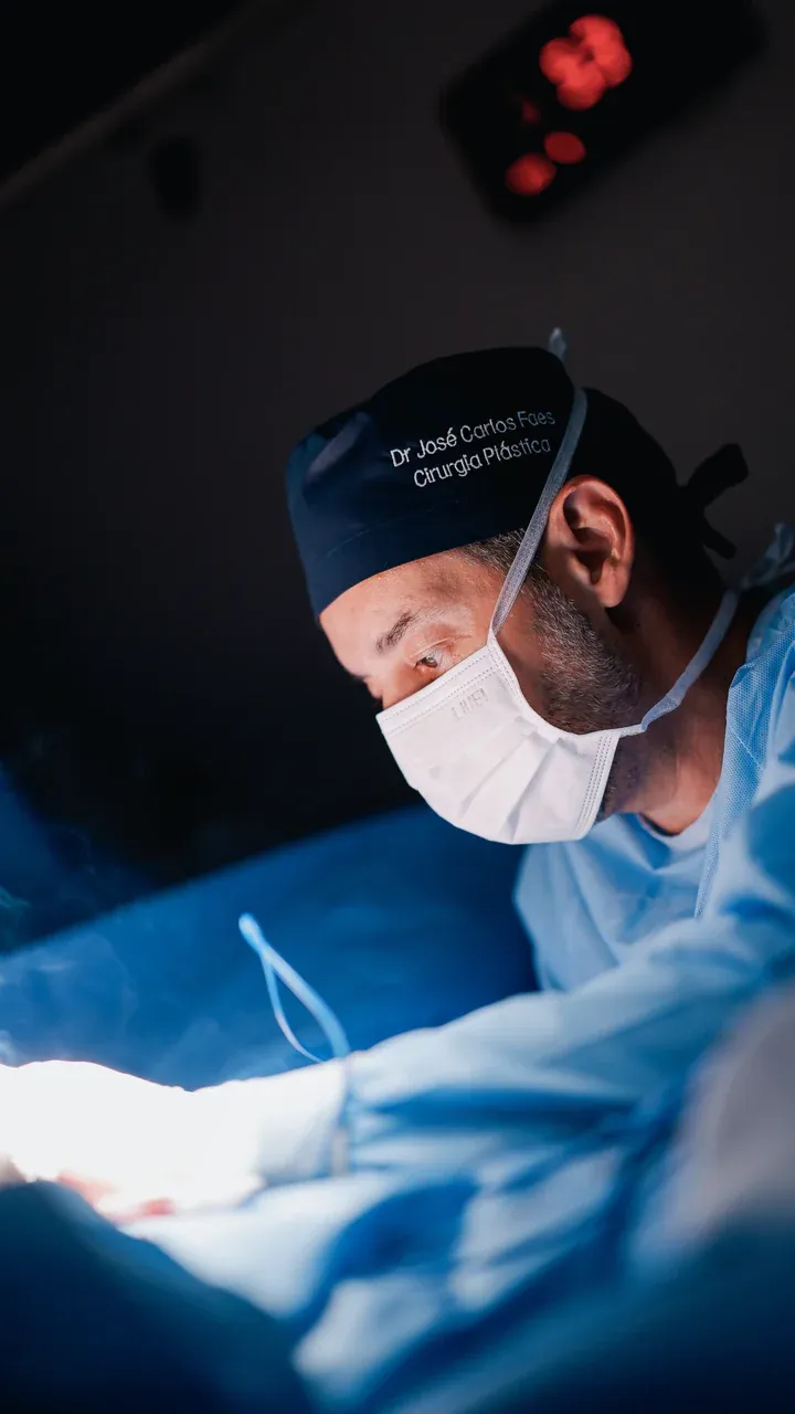 Dr. José Carlos Faes de máscara e gorro cirúrgico, concentrado sobre o campo operatório